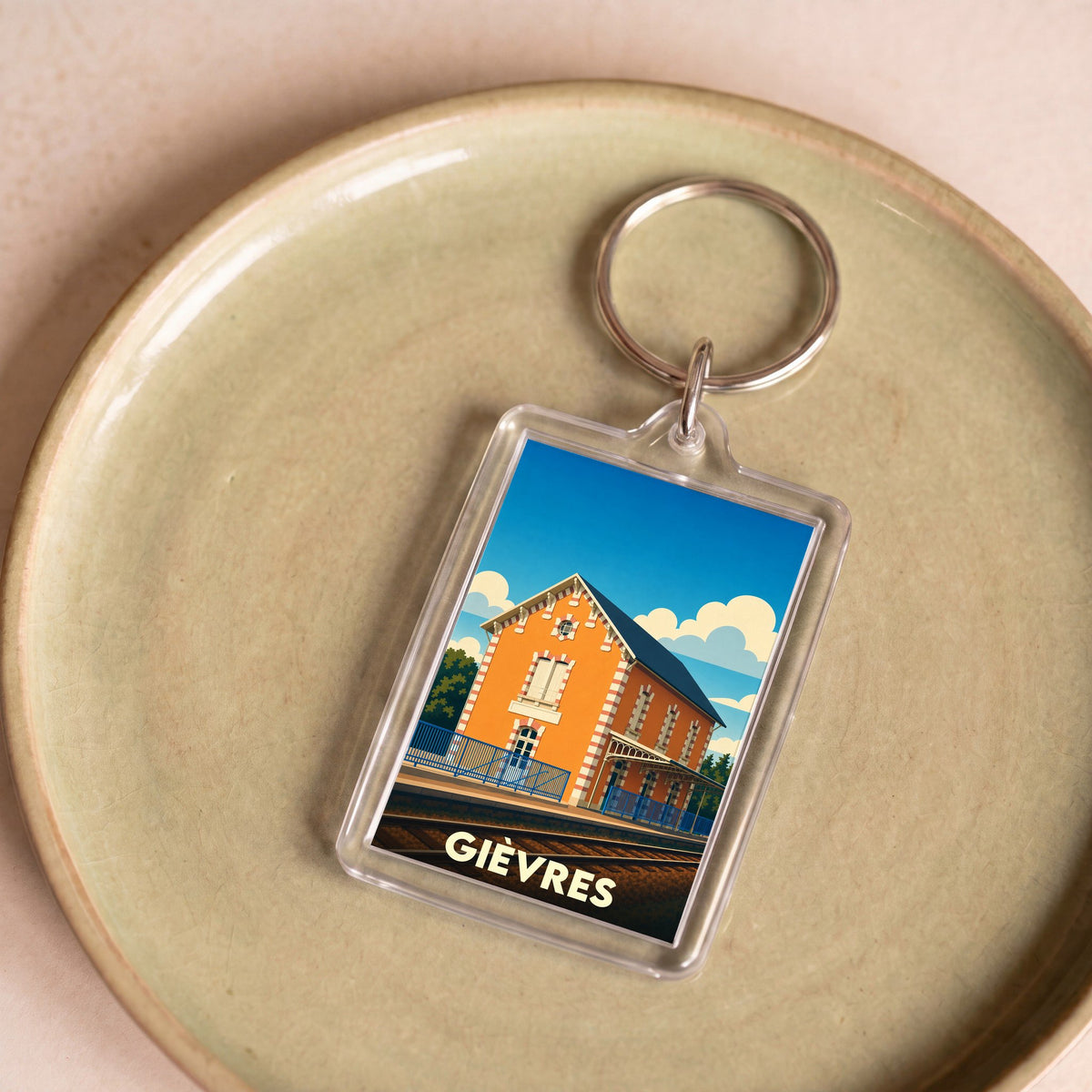 Porte-clés souvenir de la ville de Gièvres avec une illustration stylisée de sa gare ferroviaire.