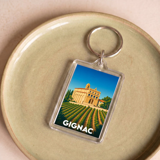 Porte-clés souvenir de la ville de Gignac avec une illustration stylisée d'un monument et de vignes.