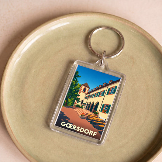 Porte-clés souvenir de la ville de Gœrsdorf avec une illustration stylisée.