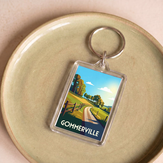 Porte-clés souvenir de la ville de Gommerville avec une illustration stylisée d'un paysage champêtre.