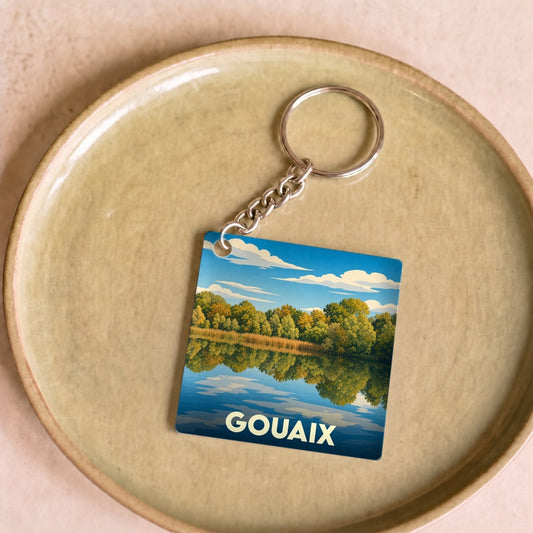Porte-clés souvenir de la ville de Gouaix avec une illustration stylisée d'un paysage lacustre.