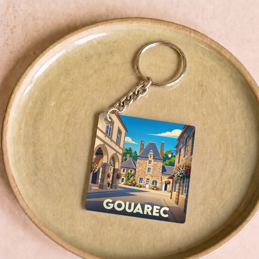 Porte-clés souvenir de la ville de Gouarec avec une illustration stylisée de son architecture traditionnelle.