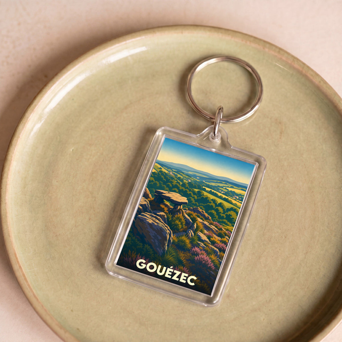Porte-clés souvenir de la ville de Gouézec avec une illustration stylisée de son paysage vallonné.