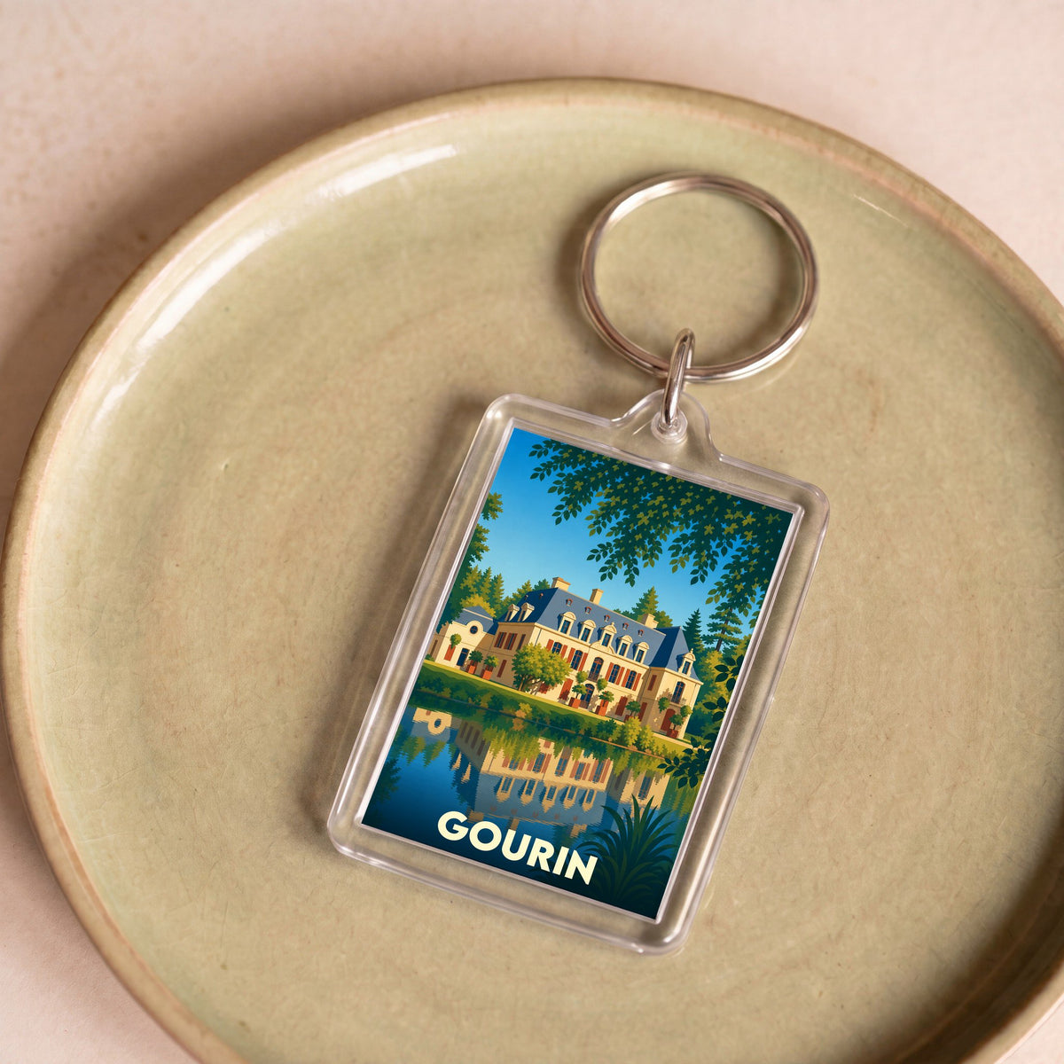 Porte-clés souvenir de la ville de Gourin avec une illustration stylisée d'un manoir se reflétant dans l'eau.