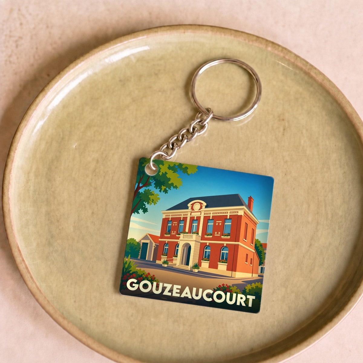 Porte-clés souvenir de la ville de Gouzeaucourt avec une illustration stylisée.