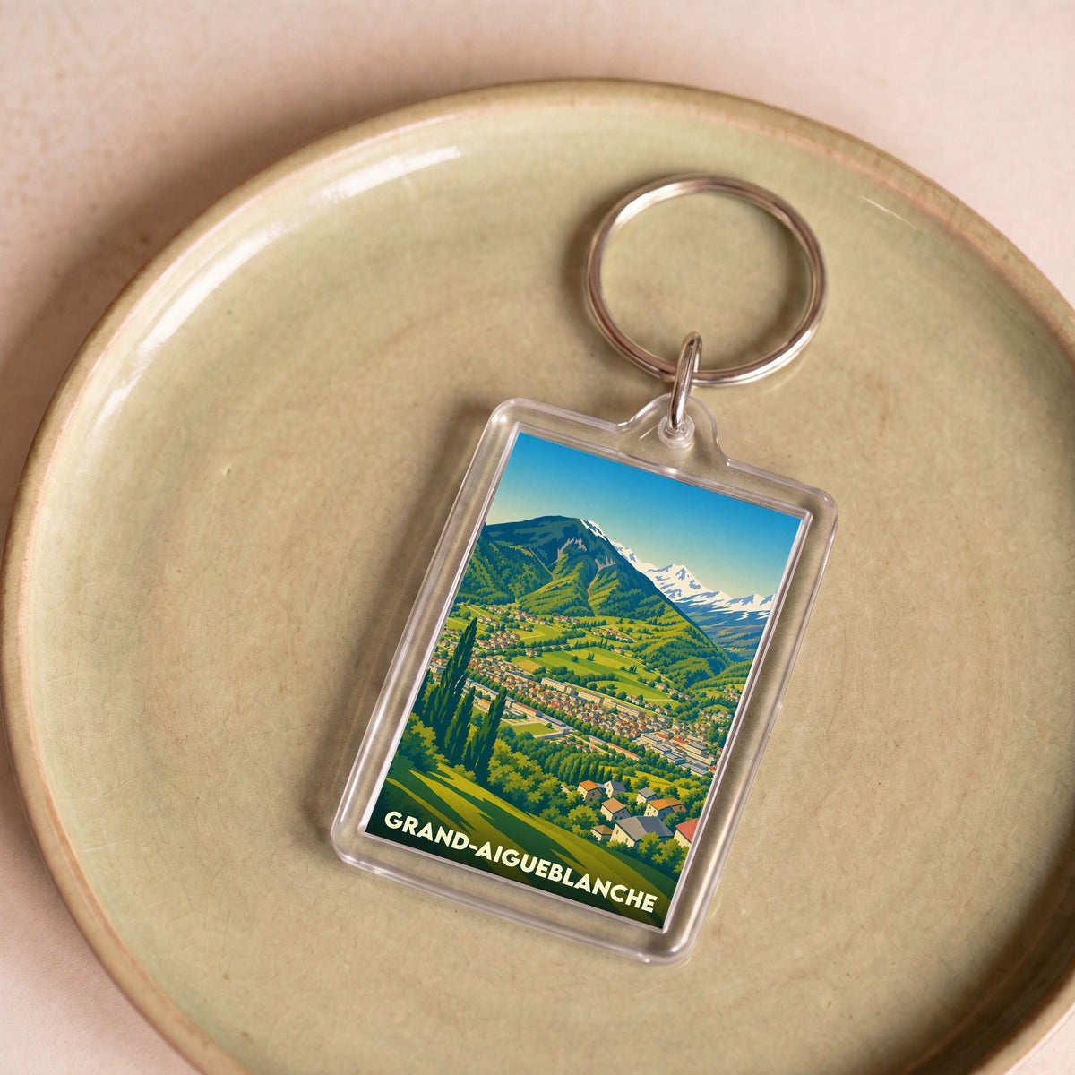 Porte-clés souvenir de la ville de Grand-Aigueblanche avec une illustration stylisée de montagne.