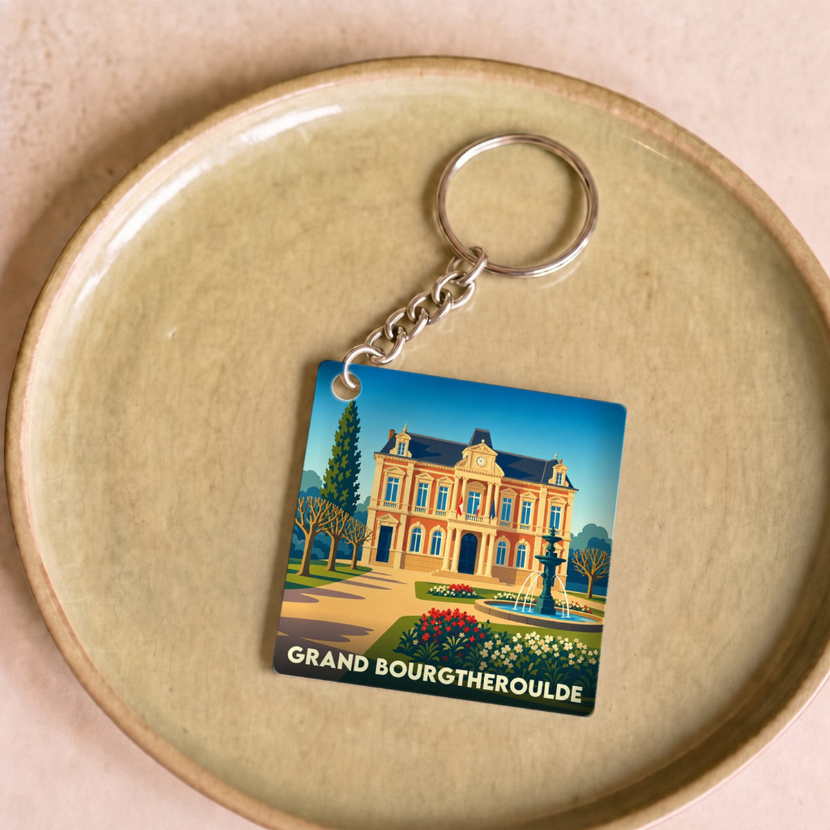 Porte-clés souvenir de la ville de Grand Bourgtheroulde avec une illustration stylisée de sa mairie.