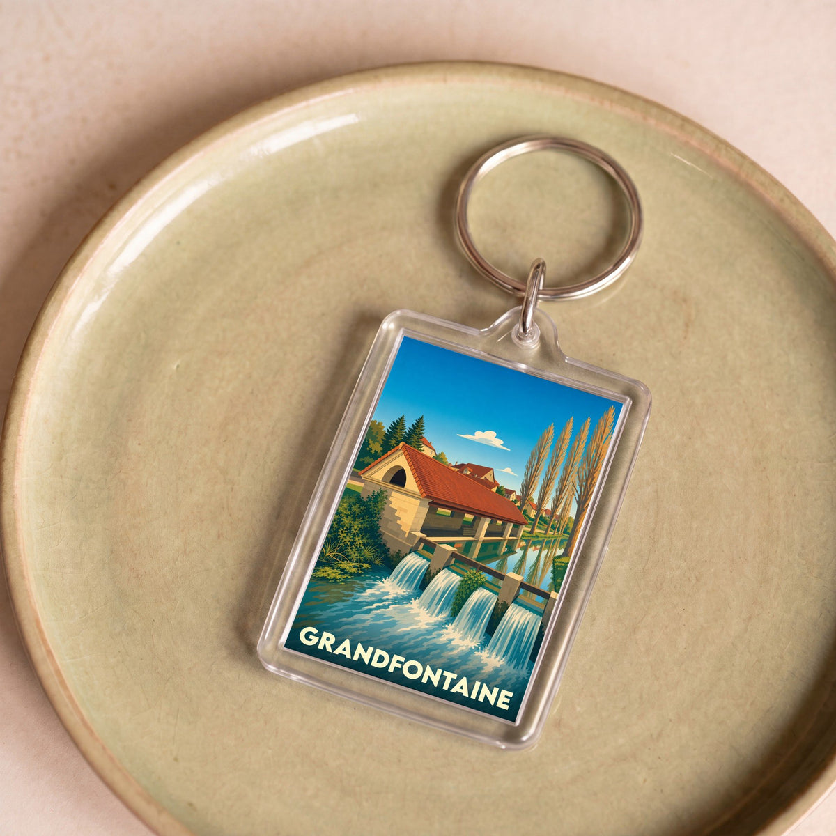 Porte-clés souvenir de la ville de Grandfontaine avec une illustration stylisée.