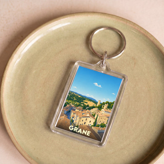 Porte-clés souvenir de la ville de Grane avec une illustration stylisée d'un village perché.