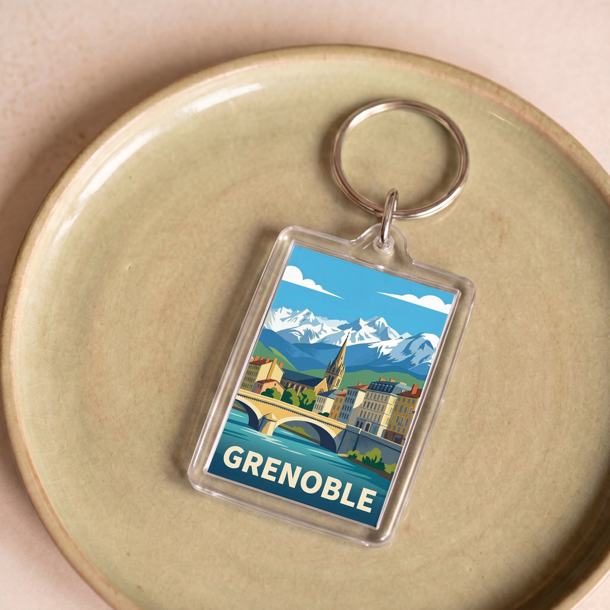 Porte-clés souvenir de la ville de Grenoble avec une illustration stylisée de son paysage urbain et montagneux.