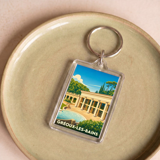 Porte-clés souvenir de la ville de Gréoux-les-Bains avec une illustration stylisée de ses thermes.