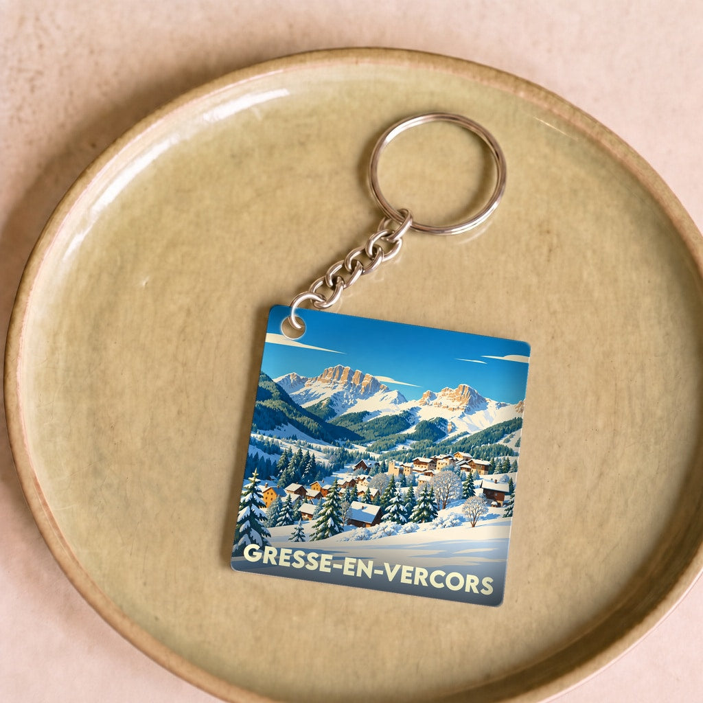 Porte-clés souvenir de Gresse-en-Vercors avec une illustration stylisée d'un village de montagne enneigé.