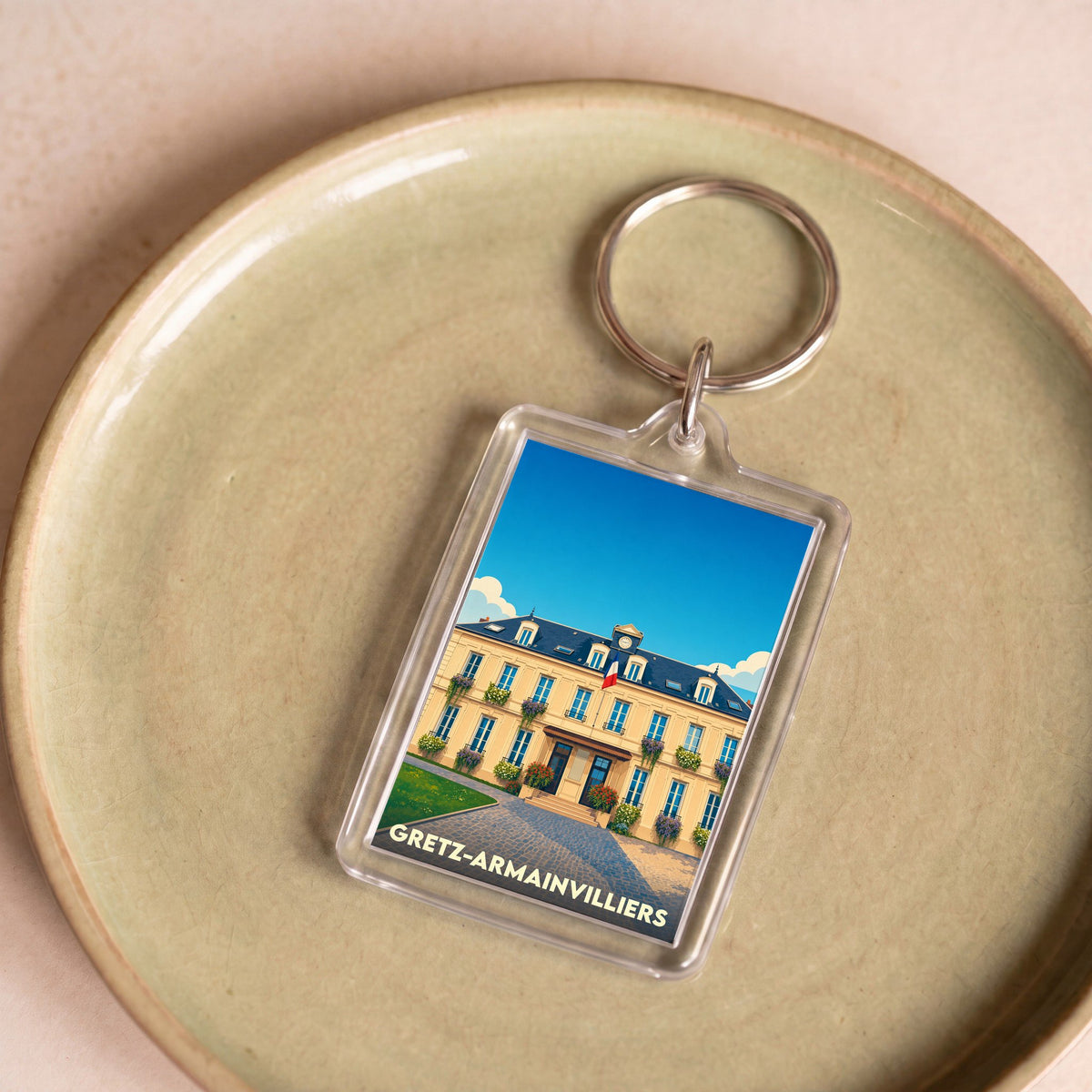 Porte-clés souvenir de la ville de Gretz-Armainvilliers avec une illustration stylisée de son hôtel de ville.