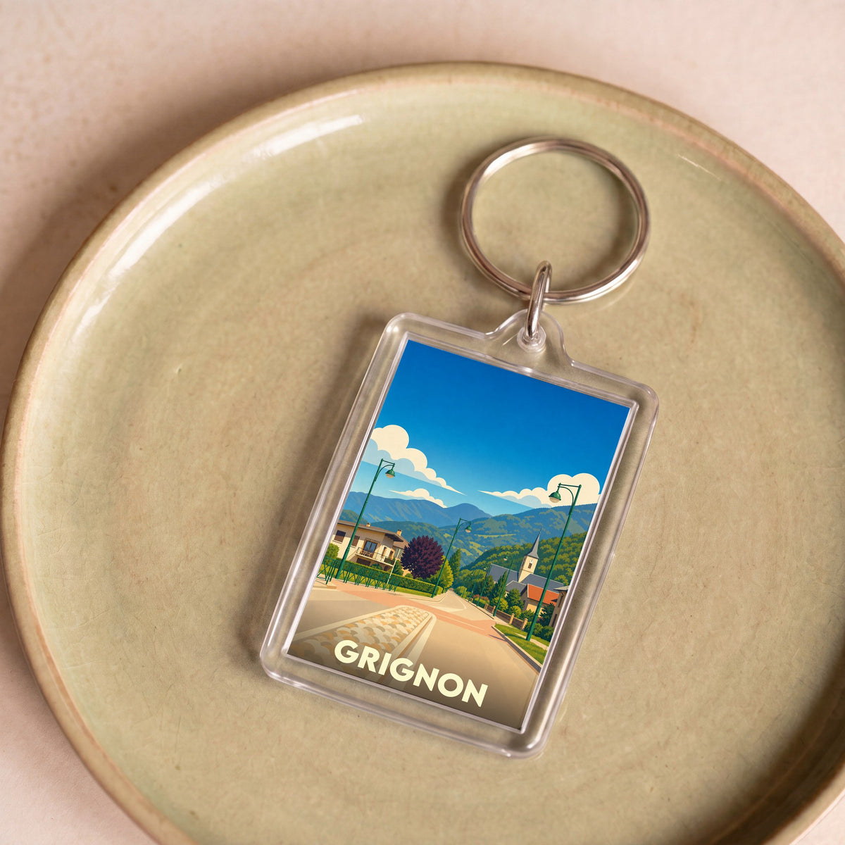 Porte-clés souvenir de la ville de Grignon avec une illustration stylisée de son paysage.