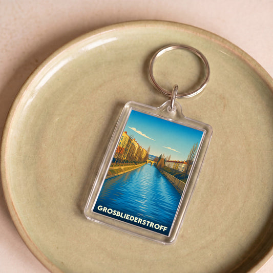 Porte-clés souvenir de la ville de Grosbliederstroff avec une illustration stylisée d'un canal bordé de maisons.