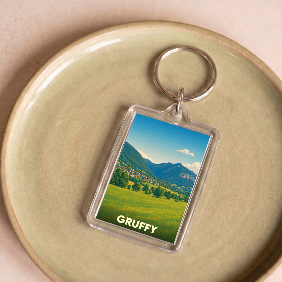 Porte-clés souvenir de la ville de Gruffy avec une illustration de paysage montagneux.