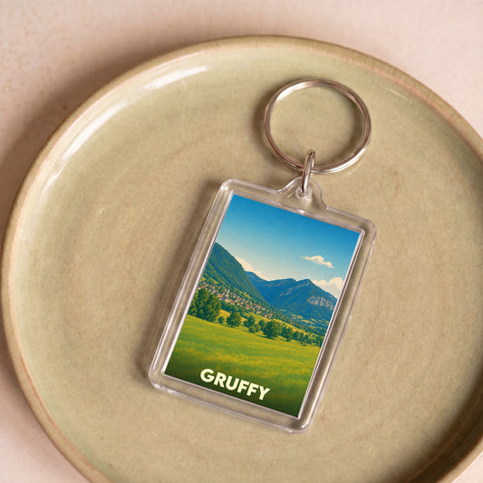 Porte-clés souvenir de la ville de Gruffy avec une illustration de paysage montagneux.