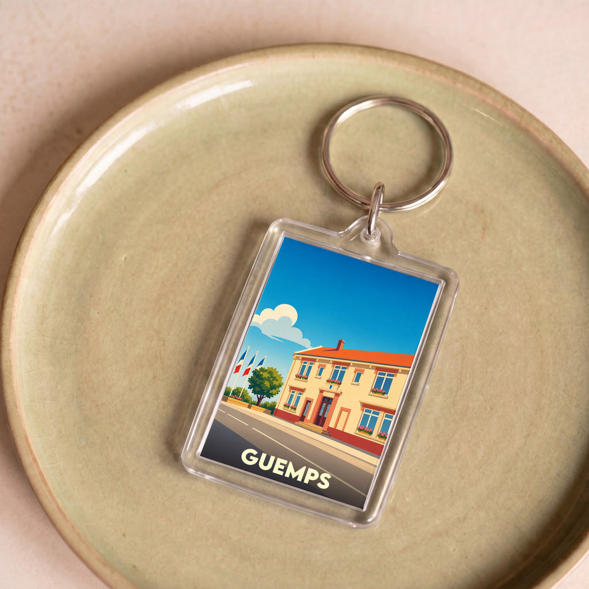 Porte-clés souvenir de la ville de Guemps avec une illustration stylisée de sa mairie.