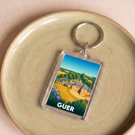 Porte-clés souvenir de la ville de Guer avec une illustration stylisée d'un manoir breton.