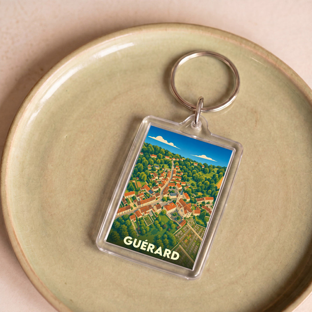 Porte-clés souvenir de la ville de Guérard avec une illustration stylisée vue du ciel.