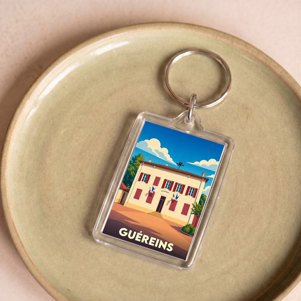 Porte-clés souvenir de la ville de Guéreins avec une illustration stylisée de la mairie.