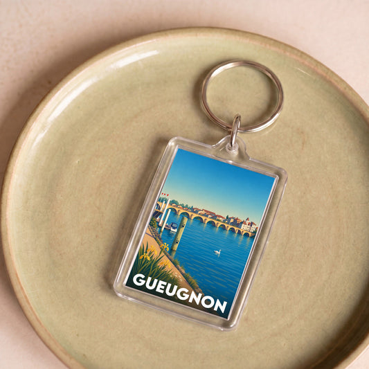 Porte-clés souvenir de la ville de Gueugnon avec une illustration stylisée d'un paysage fluvial.