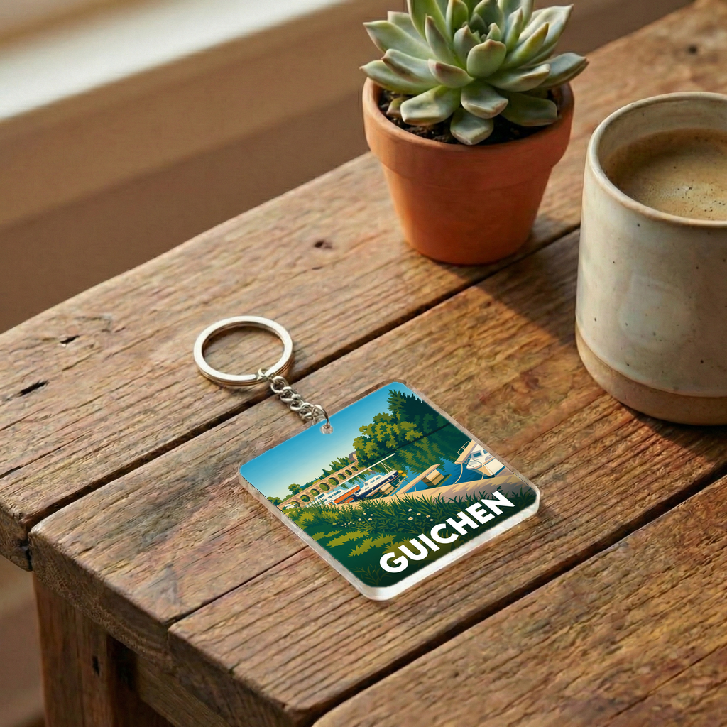 Porte-clés souvenir de la ville de Guichen avec une illustration stylisée d'un paysage fluvial.
