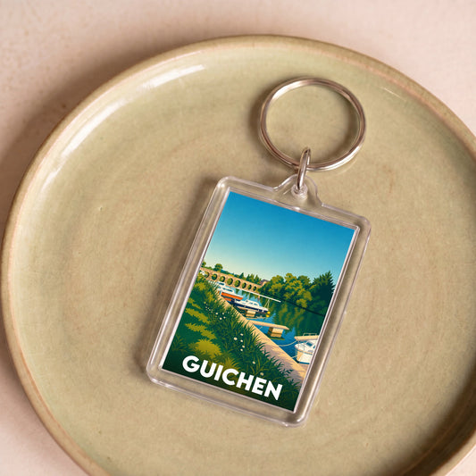 Porte-clés souvenir de la ville de Guichen avec une illustration stylisée d'un paysage fluvial.