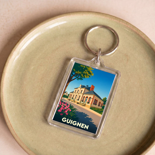 Porte-clés souvenir de la ville de Guignen avec une illustration stylisée de sa mairie.