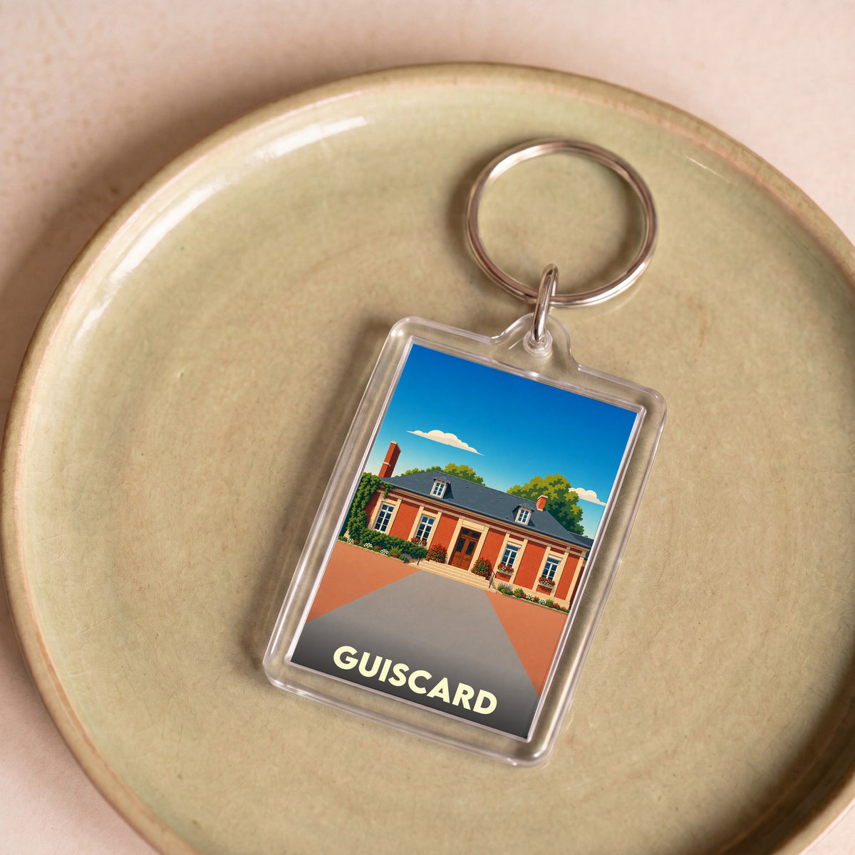Porte-clés souvenir de la ville de Guiscard avec une illustration stylisée.