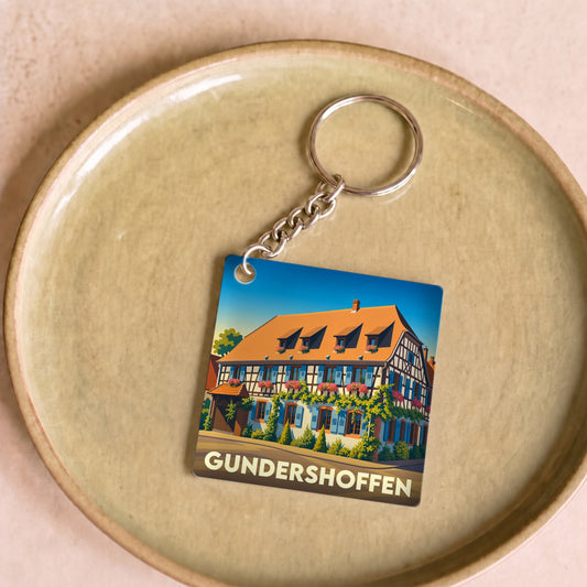 Porte-clés souvenir de la ville de Gundershoffen avec une illustration stylisée d'une maison à colombages.