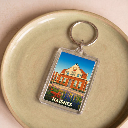 Porte-clés souvenir de la ville de Haisnes avec une illustration stylisée de son hôtel de ville fleuri.