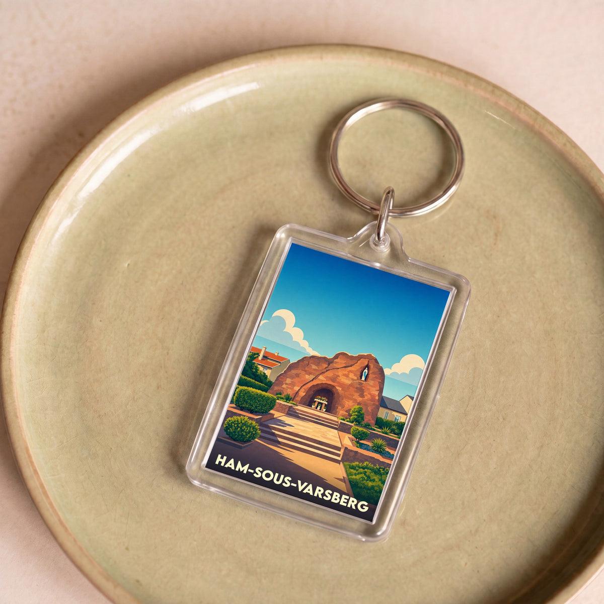 Porte-clés souvenir de la ville de Ham-sous-Varsberg avec une illustration stylisée d'une grotte sous un ciel bleu.
