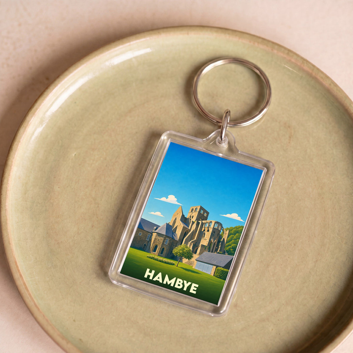 Porte-clés souvenir de la ville de Hambye avec une illustration stylisée de son abbaye.