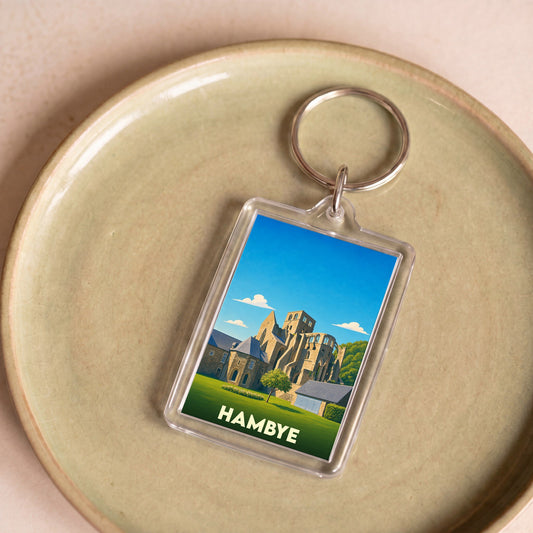 Porte-clés souvenir de la ville de Hambye avec une illustration stylisée de son abbaye.