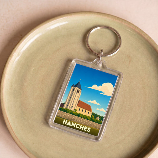 Porte-clés souvenir de la ville de Hanches avec une illustration stylisée de son église.