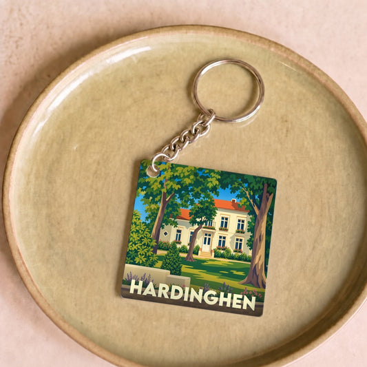 Porte-clés souvenir de la ville de Hardinghen avec une illustration stylisée d'une demeure entourée de verdure.