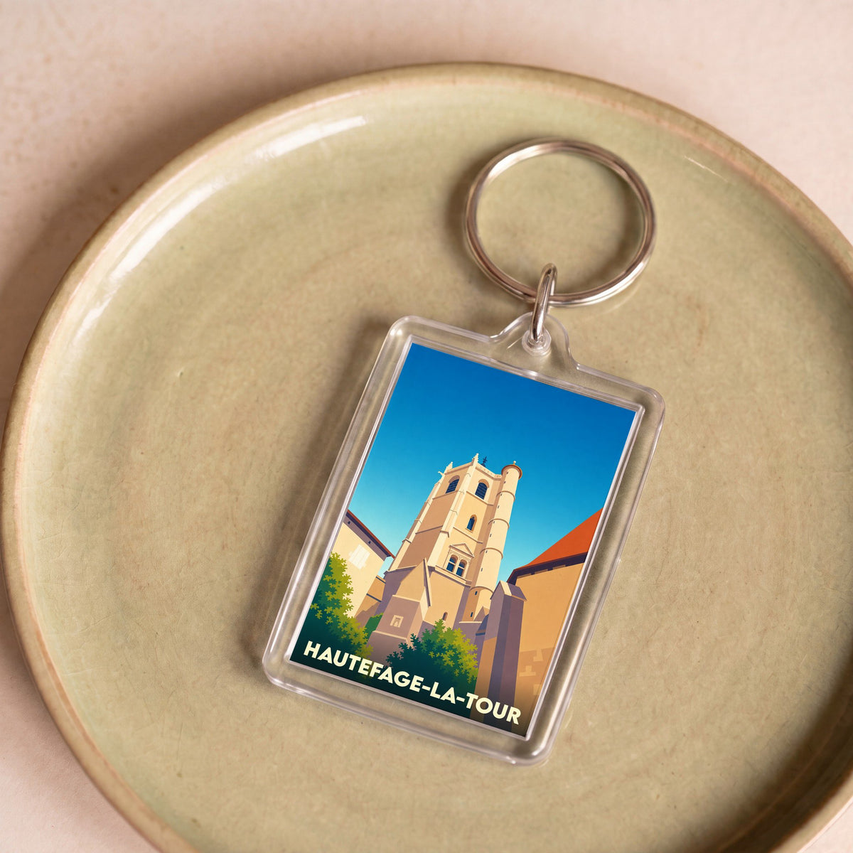 Porte-clés souvenir de la ville de Hautefage-la-Tour avec une illustration stylisée de sa tour historique.