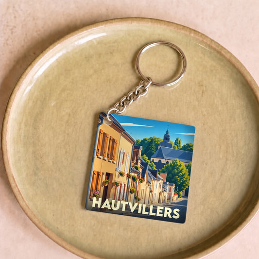 Porte-clés souvenir de la ville de Hautvillers avec une illustration stylisée de ses rues et de son abbaye.