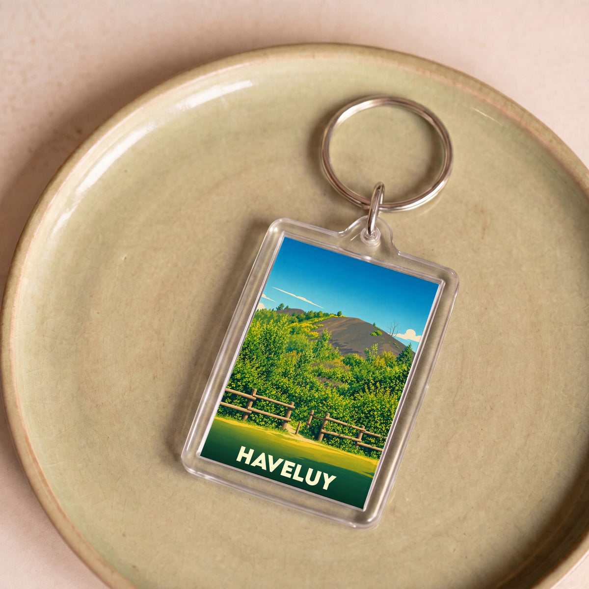 Porte-clés souvenir de la ville de Haveluy avec une illustration stylisée de paysage naturel.