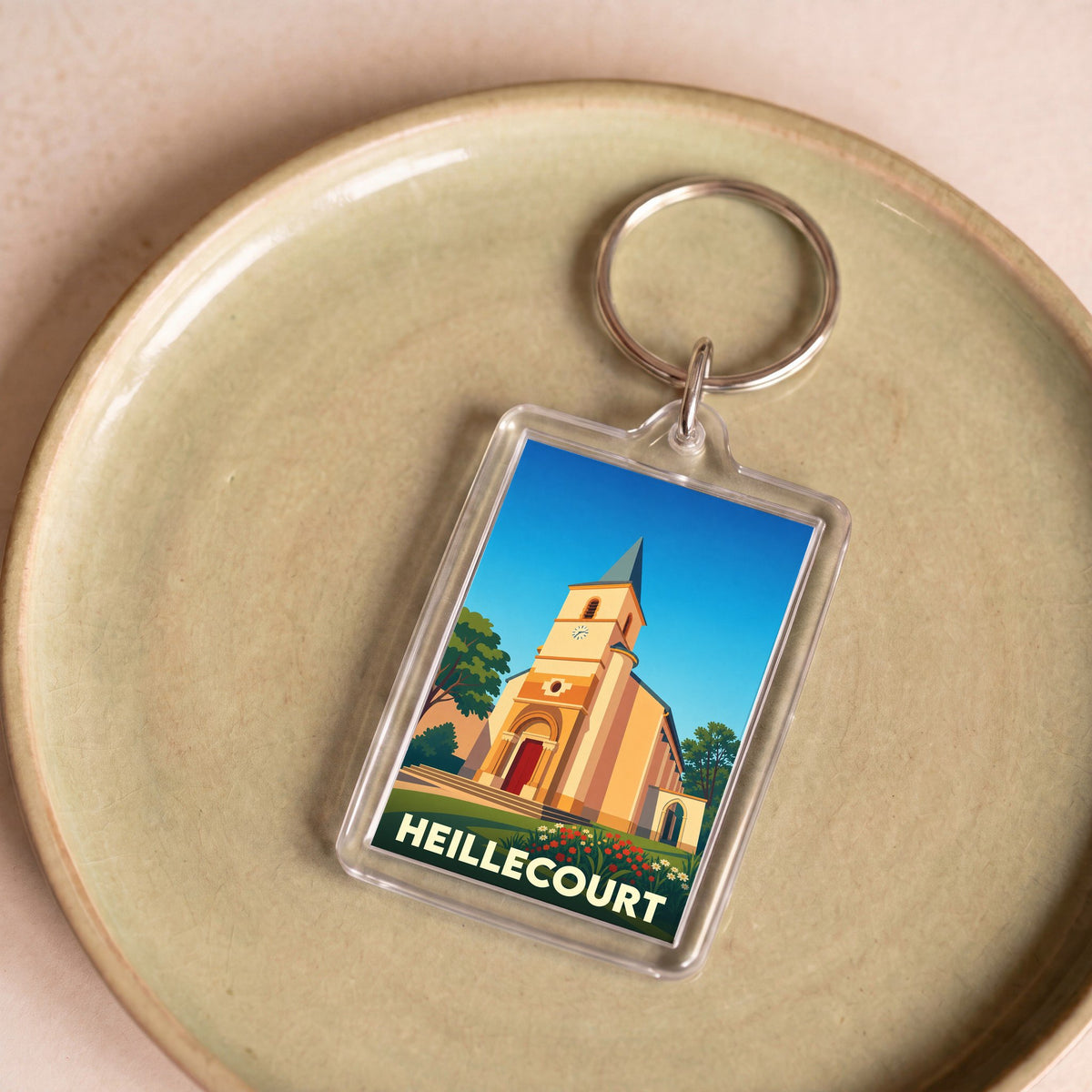 Porte-clés souvenir de la ville de Heillecourt avec une illustration stylisée de son église.