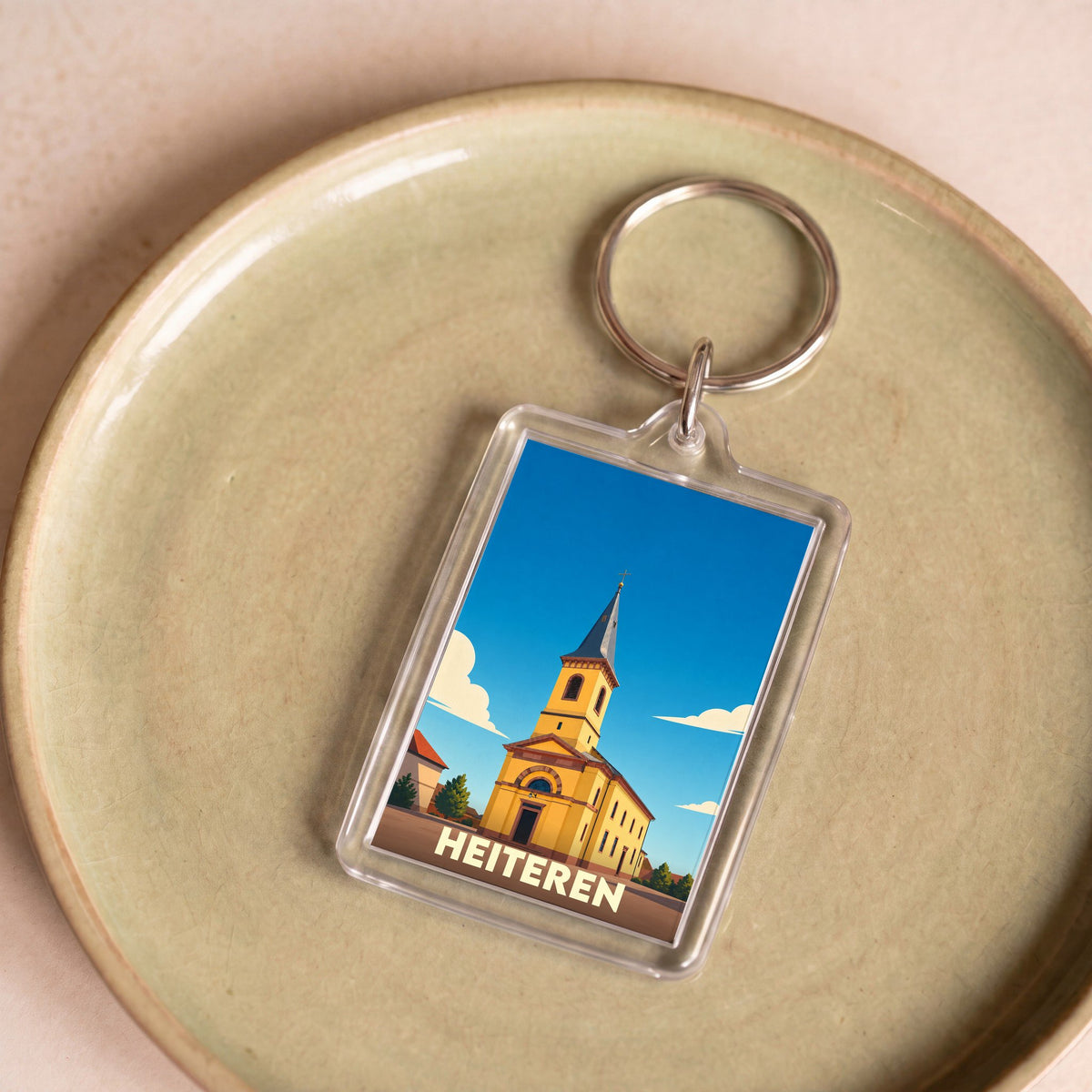 Porte-clés souvenir de la ville de Heiteren avec une illustration stylisée d'une église sous un ciel bleu.