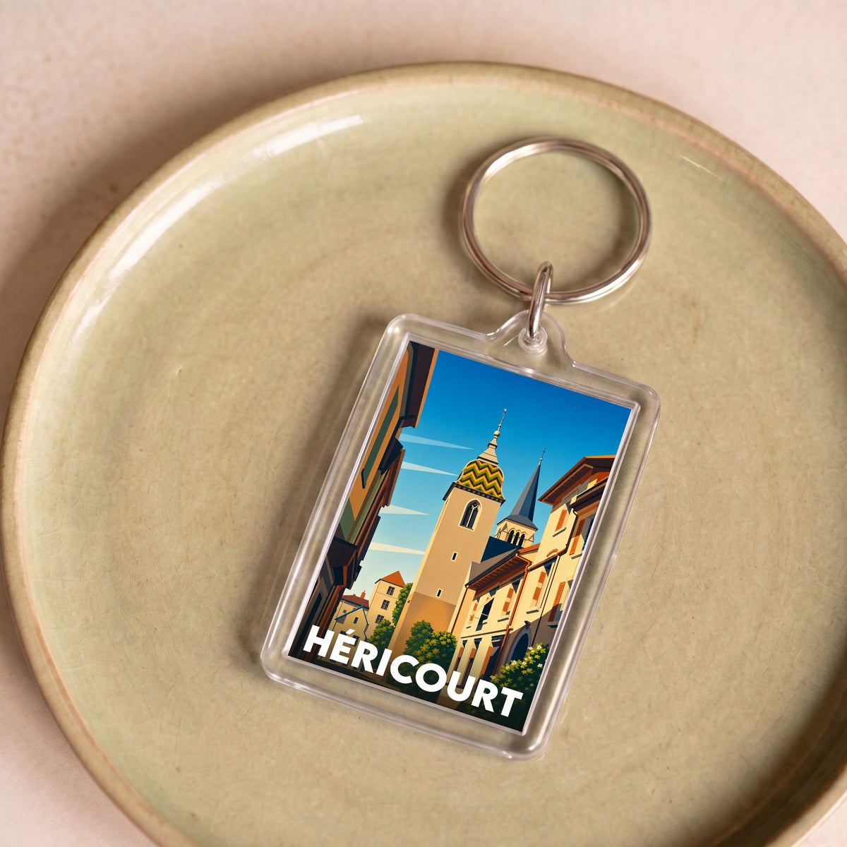Porte-clés souvenir de la ville de Héricourt avec une illustration stylisée.
