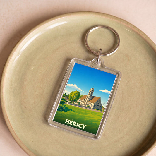 Porte-clés souvenir de la ville de Héricy avec une illustration stylisée d'une église sous un ciel bleu.