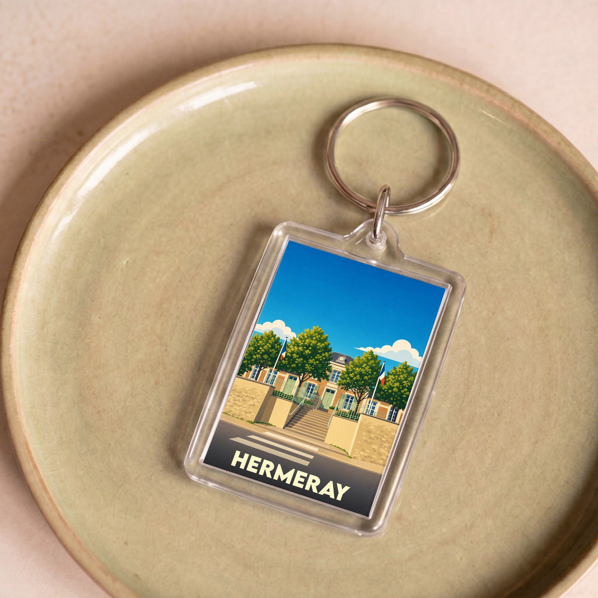 Porte-clés souvenir de la ville de Hermeray avec une illustration stylisée de la mairie.