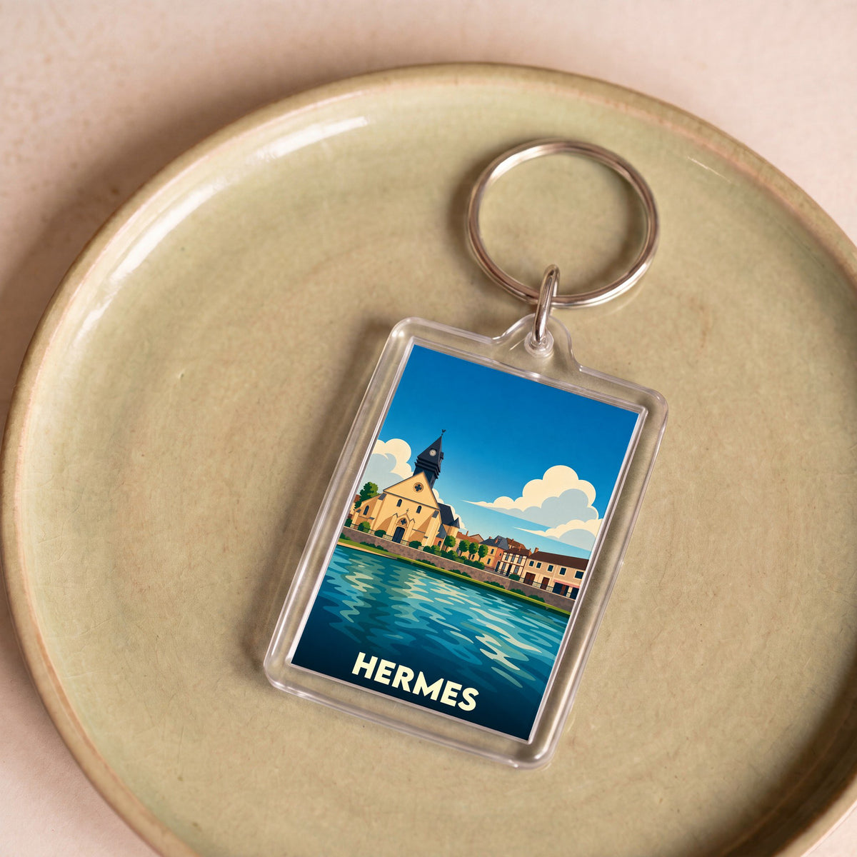 Porte-clés souvenir de la ville de Hermes avec une illustration stylisée d'un paysage urbain au bord de l'eau.