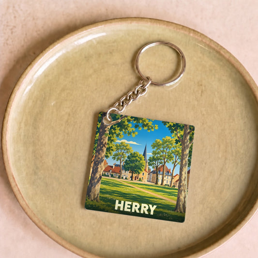 Porte-clés souvenir de la ville de Herry avec une illustration stylisée d'un parc arboré et de son église.