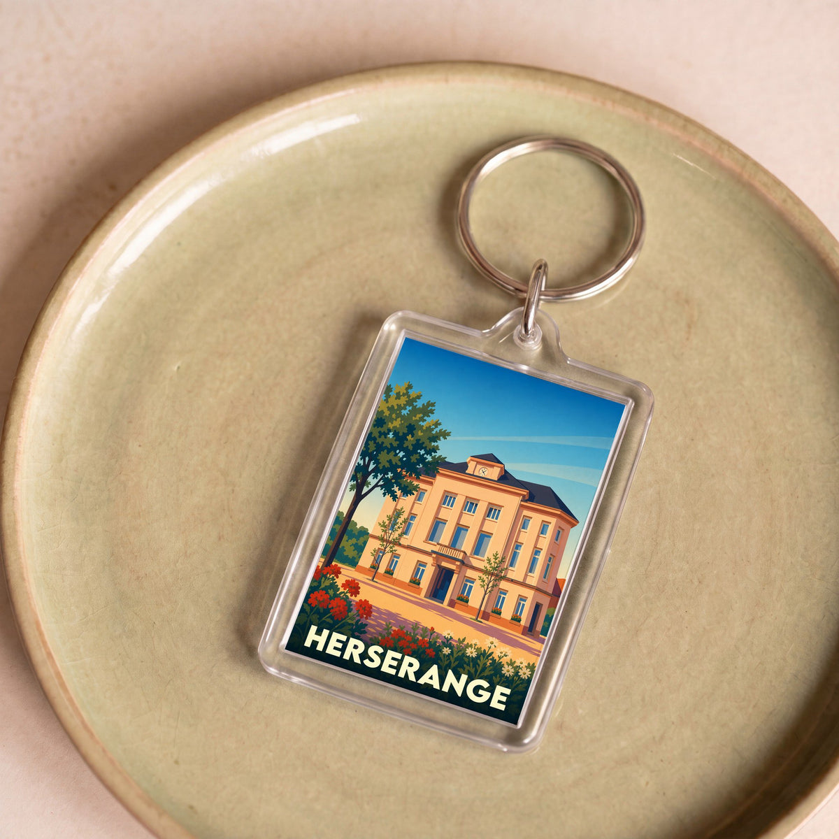 Porte-clés souvenir de la ville de Herserange avec une illustration stylisée de son hôtel de ville.