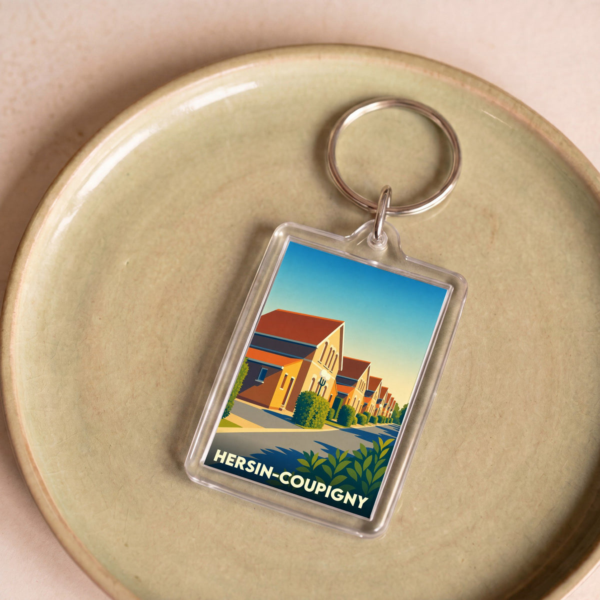 Porte-clés souvenir de la ville de Hersin-Coupigny avec une illustration stylisée.