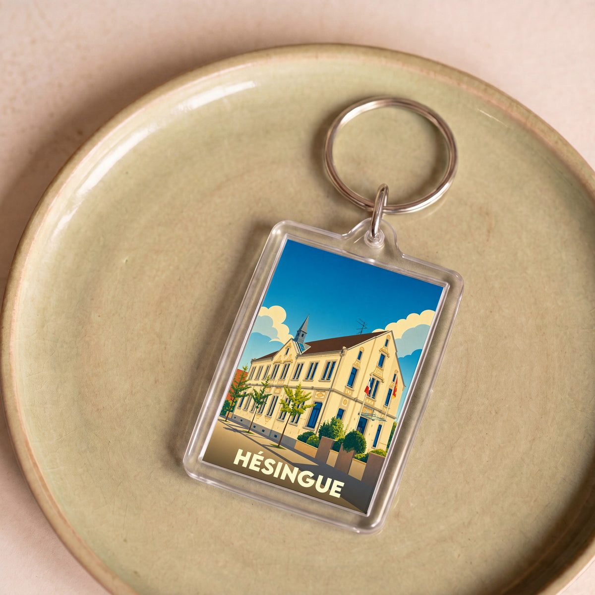 Porte-clés souvenir de la ville de Hésingue avec une illustration stylisée.